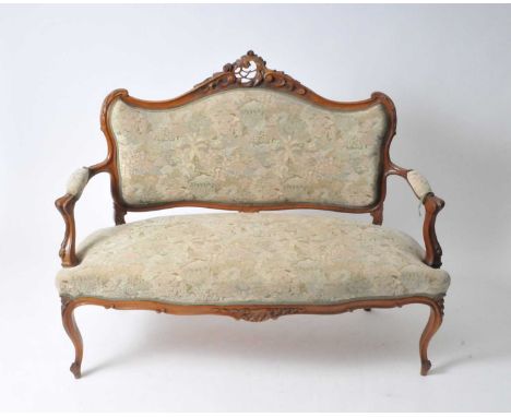 A small French walnut framed upholstered parlour settee, with scrolling carved frame, covered in a light coloured floral fabr