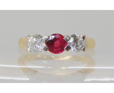 An 18ct gold ruby and diamond three stone ring, set with two estimated approx 0.30ct of brilliant cut diamonds to either side