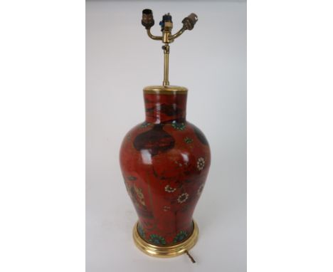 A Chinese baluster table lamp painted and applied with polychrome enamels on a red ground with a family in a garden, beneath 