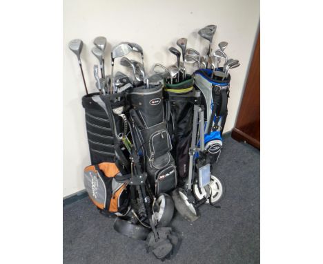 Four golf bags containing a large quantity of golfing irons and drivers to include Howson, Spalding etc together with two fol