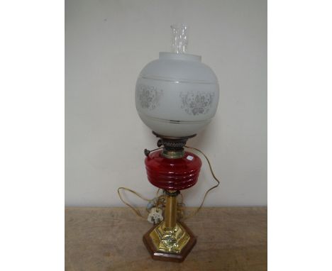 A Duplex brass oil lamp on wooden base with red glass reservoir, opaque shade and chimney (converted) 