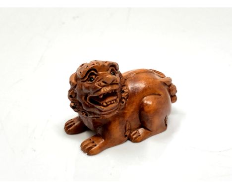 A carved hardwood netsuke -  Lion