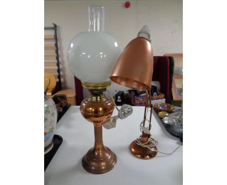 A copper and brass oil lamp with chimney and shade (converted), together with a mid 20th century copper and teak angle poised
