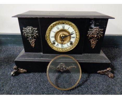 A 19th century cast iron mantel clock with brass and enamelled dial and metal mounts 
