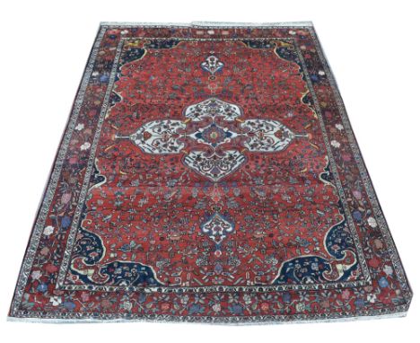 Bakhtiari carpet, the quatrefoil floral medallion surrounded by foliate sprays on red ground, 260 x 357cms.