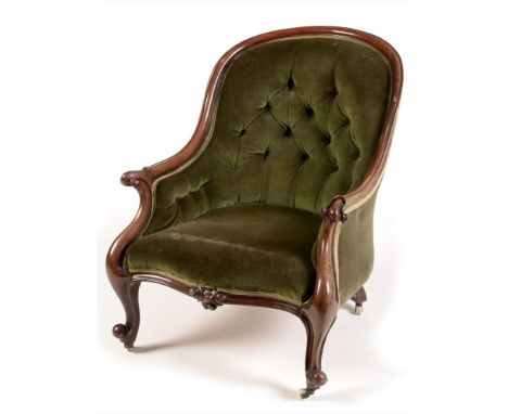 A Victorian mahogany framed easy armchair , the mahogany frame enclosing a green velour button back and sides, the arms with 