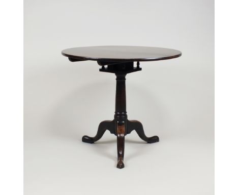 A mahogany tripod table, part 18th century, the circular tilt top above a bird cage action and raised on a tapering gun barre