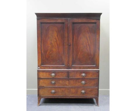 A George III mahogany linen press, the pair of panelled doors with oval ebony and satinwood inaly enclosing an adapted interi