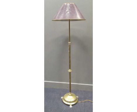 An early 20th century brass adjustable standard lamp on a circular base with paw feet, 162cm high