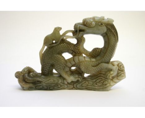 A Chinese pale green hardstone carving in the form of a mythical dragon on a cloud plinth base with a small mammal upon its b