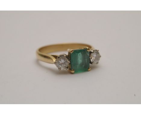 A ladies 18ct yellow gold ring set with a central emerald flanked by brilliant cut diamonds