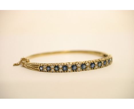 A ladies 9ct gold bangle set with a single round of round cut blue sapphires spaced by diamonds