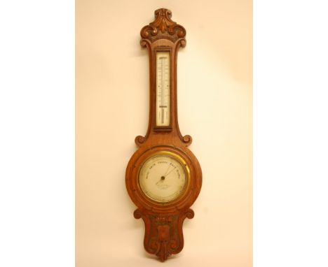 An oak barometer, the carved top above an applied thermometer box 