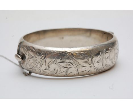 A silver bangle with foliate decoration 