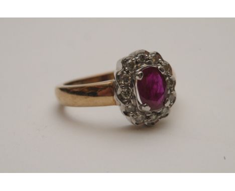 A ladies 9ct yellow gold ring set with a central oval cut ruby with diamond surround