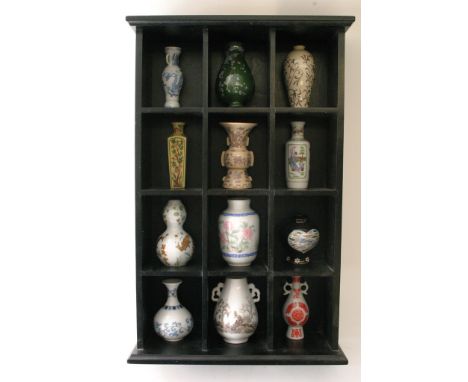 A black painted display shelf housing miniature Chinese style vases