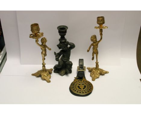  A small bronze cherub figure, a horse brass and two brass candle sticks 