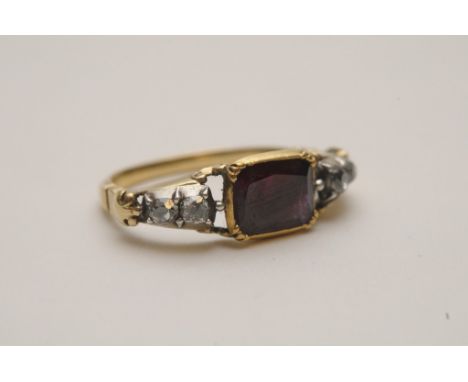A fine quality 18th century antique gold ring set with a large central ruby flanked by two diamonds to each shoulder 