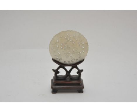 A Chinese pierced jade carving of disc form with small wooden stand, Diameter 5.5cm approximately 