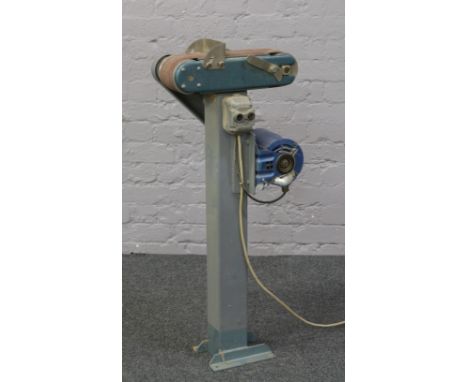 A 10cm belt sander mounted on a steel floor stand with 220 volt motor.