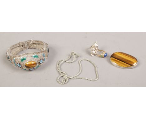 A white metal tigers eye and enamel bangle, a tigers eye brooch, two dress rings and a chain.