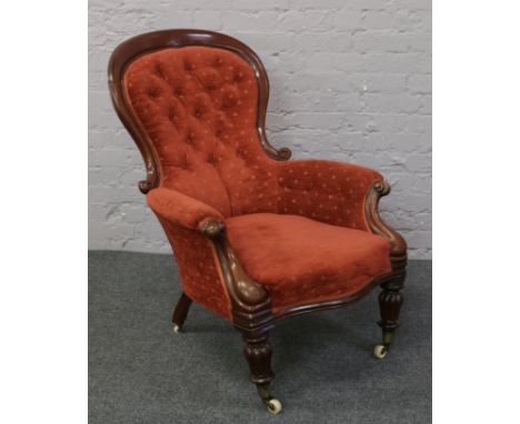 A spoon back arm chair with deep button upholstery, raised on carved supports.