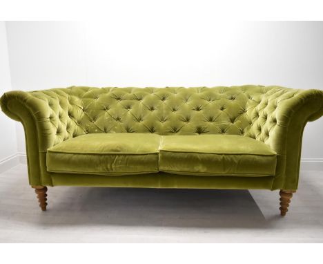 A contemporary button back Chesterfield style two seater settee, with scroll arms raised on turned supports upholstered in gr