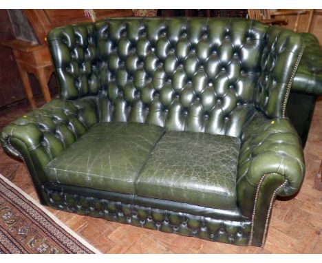 Green Chesterfield two seater leather wing back sofa. Condition report: see terms and conditions