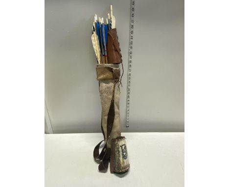 A selection of hand made Native American Indian style arrows and two arm protectors  together in a hand made hide arrow pouch