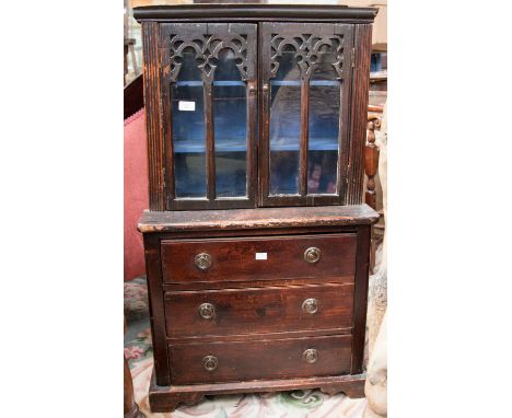 A 19th century miniature bookcase chest, the glazed cabinet with Gothic tracery doors, above a three drawer chest on ogee bra