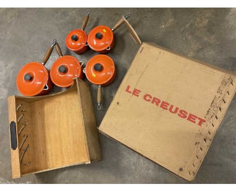 Graduated set of five Le Creuset lidded saucepans, with hanging shelf, boxed