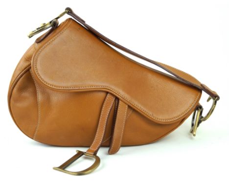 Christian Dior: A tan leather saddle bagThe smooth tan leather with white stitching, flat shoulder strap with brushed gold to