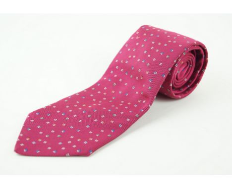 An Hermes silk tieOf typical form, with ribbed, deep red ground, with a scattered, multi-coloured 'H' design throughout, leng