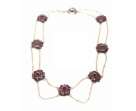 A Victorian Bohemian garnet necklaceComposed of graduated rose-cut garnet clusters, set between parallel yellow metal swag tr