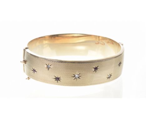 A Victorian gem-set hinged bangleWith engine turned detail throughout, each gypsy set gemstone delicately scattered to one si