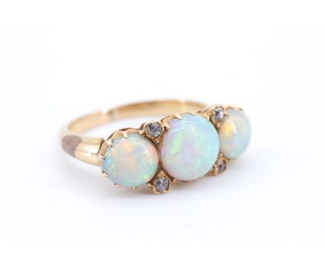 A handsome three-stone opal and diamond ring, comprising three circular opal cabochons of 7 mm and 6 mm divided by pairs of s