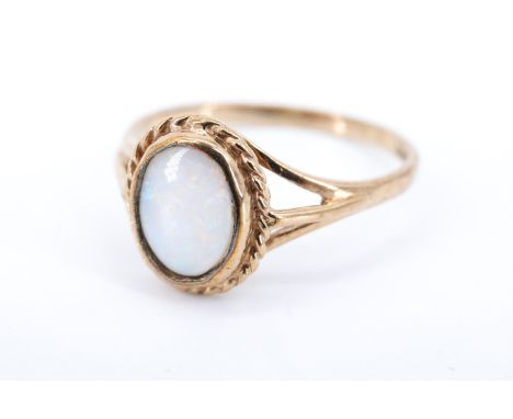 A lady's opal and 9 ct gold finger ring, having an oval opal in a rubbed over setting within a rope twist border, between ope