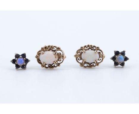 A pair of opal stud earrings, each 7 x 5 mm oval opal set on a frame of adorsed scrolls, with 9 ct gold pin backs, together w