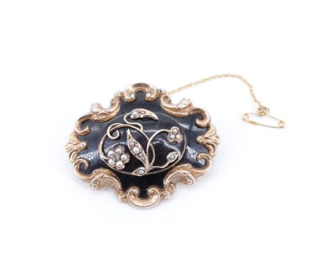 A Victorian yellow metal, enamel and seed pearl mourning brooch, the central oval panel having a vine set with seed pearls on