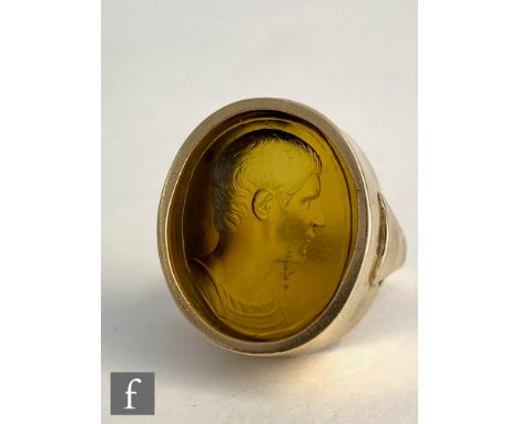 A 9ct ring with central signed amber glass intaglio carved oval depicting head and shoulder profile of a young man, possibly 