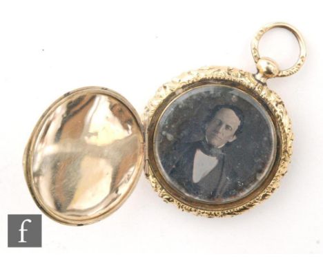 A 19th Century 9ct double sided circular locket with a portrait daguerreotype of a man to one side and a woman to the other, 