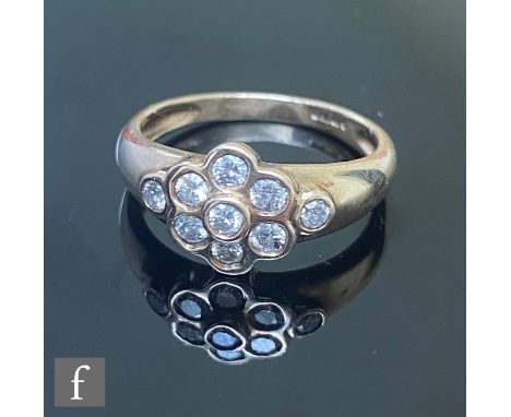 A 9ct hallmarked diamond daisy cluster ring, seven collar set diamonds with a further diamond set to each shoulder, total dia