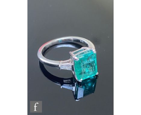 A modern 18ct hallmarked white gold emerald and diamond ring, central emerald cut emerald length 9mm, width 7.5mm, claw set a