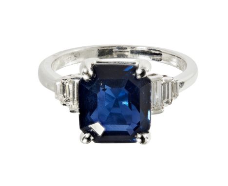 An Art Deco style sapphire and diamond set ringclaw set with a trap cut sapphire, flanked to either side by three tapering ba