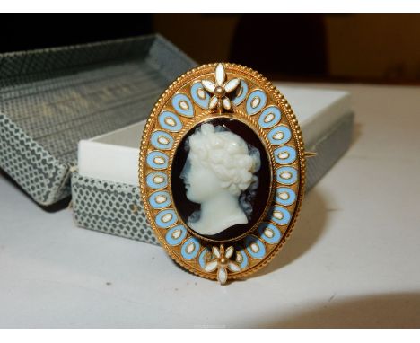 An unmarked gold set, hardstone Cameo brooch depicting a classical female head in a gold wirework, blue and white enamel fram