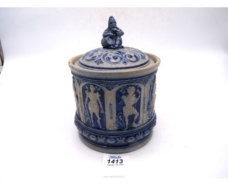 A Westerwald lidded Tobacco Jar with panels depicting Knights in armour and a seated gnome with a barrel finial, (some chips 