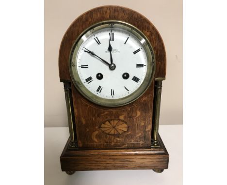 An early twentieth century inlaid oak dome topped mantel clock with enamel dial retailed by Reids of Newcastle 