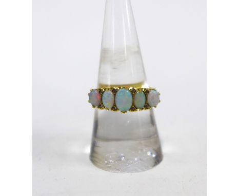 An 18ct gold and opal five stone ring, claw set with graduating opals with eight diamond points in-between, on a scrolling pi