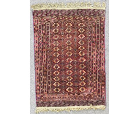An antique Saryk Turkmen rug woven in navy blue, orange and ivory with three rows each of twelve small guls on a brown ground