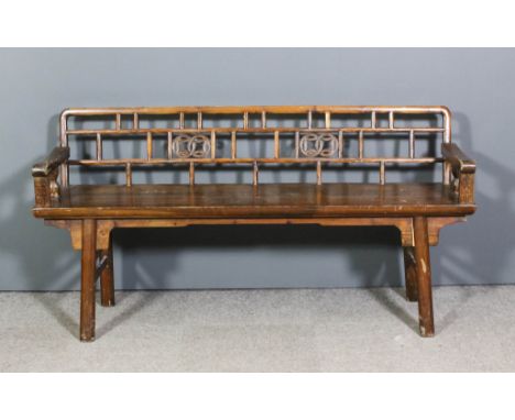 A Chinese stained pine bench, the pierced back with twin circular motifs, wood seat, on angled legs, 64ins wide (1164mm) (20t